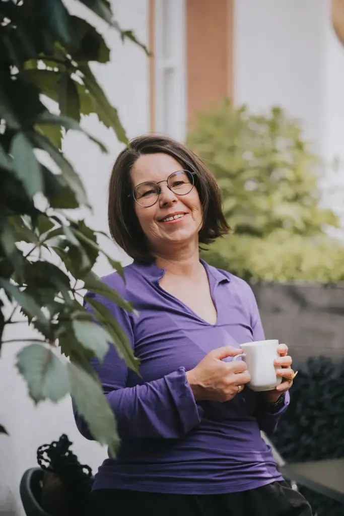 June Morris trinkt Kaffee auf der Terrasse