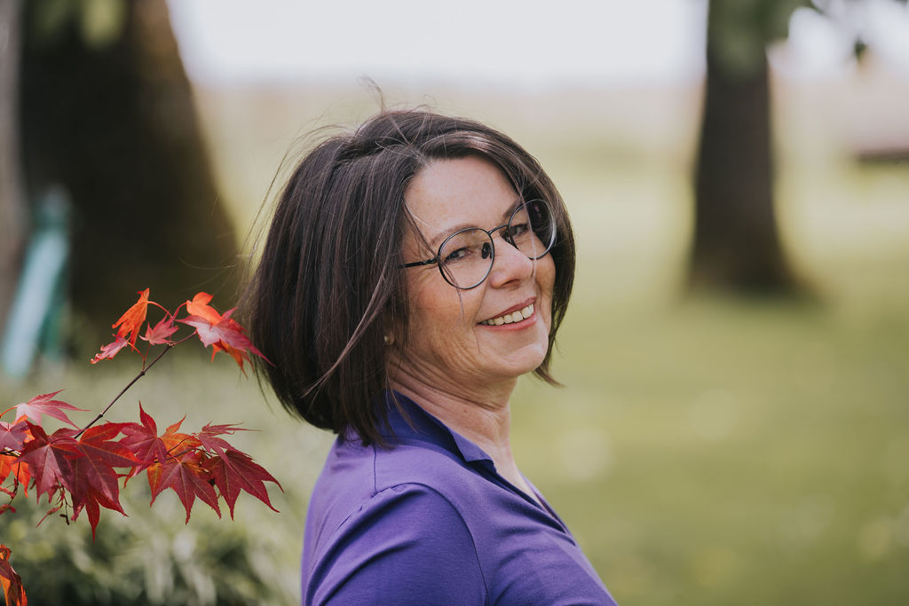 June Morris steht im Garten und lacht